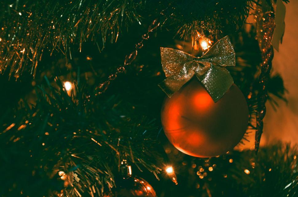 Free Image of Christmas tree with glowing lights and red ornament ball 