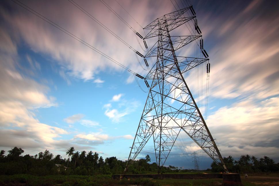 Free Image of Electric tower against a fast-moving cloudy sky 