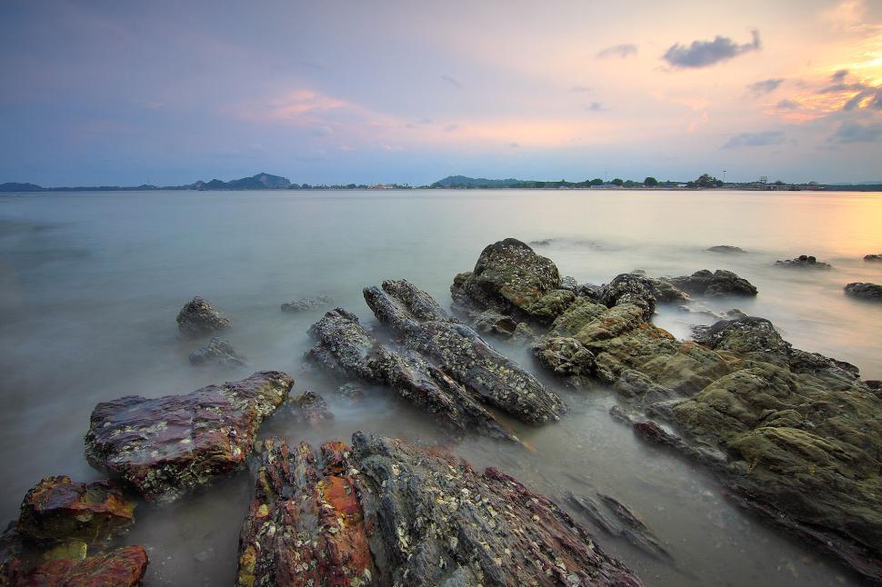 Free Image of Serene rocky beach at sunset with distant horizon views. 