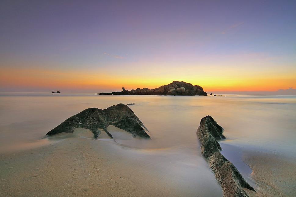 Free Image of Serene beach sunset with rocky islands in the distance 