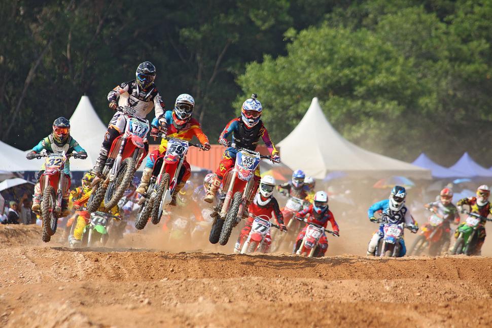 Free Image of Dirt bike race with riders airborne over dusty track 