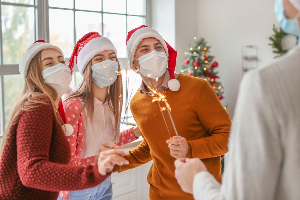Free Image of Christmas celebration with sparklers and Santa hats 