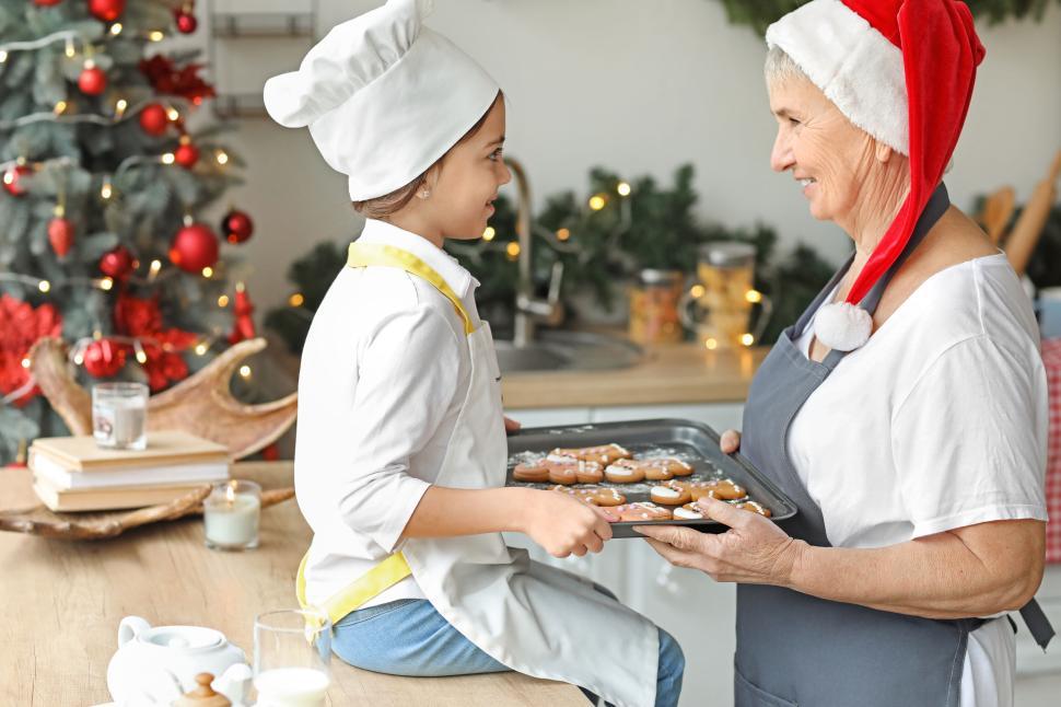 Free Image of Child and senior bake Christmas gingerbread cookies. 