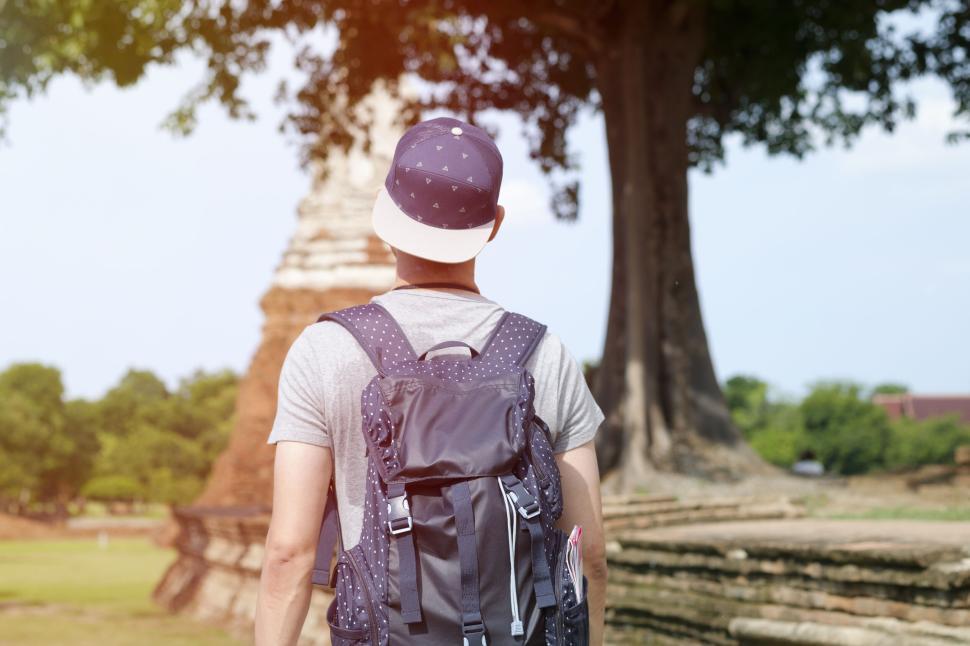 Free Image of Man wearing cap and backpack exploring historical site. 