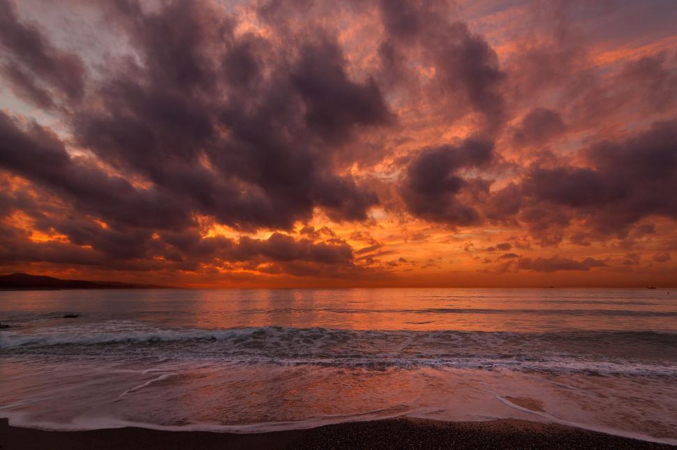 Free Image of Sunset over the ocean with dramatic clouds in sky. 