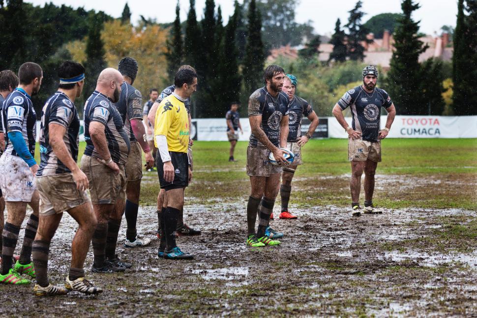 Free Image of Rugby team with referee on a muddy field during game 