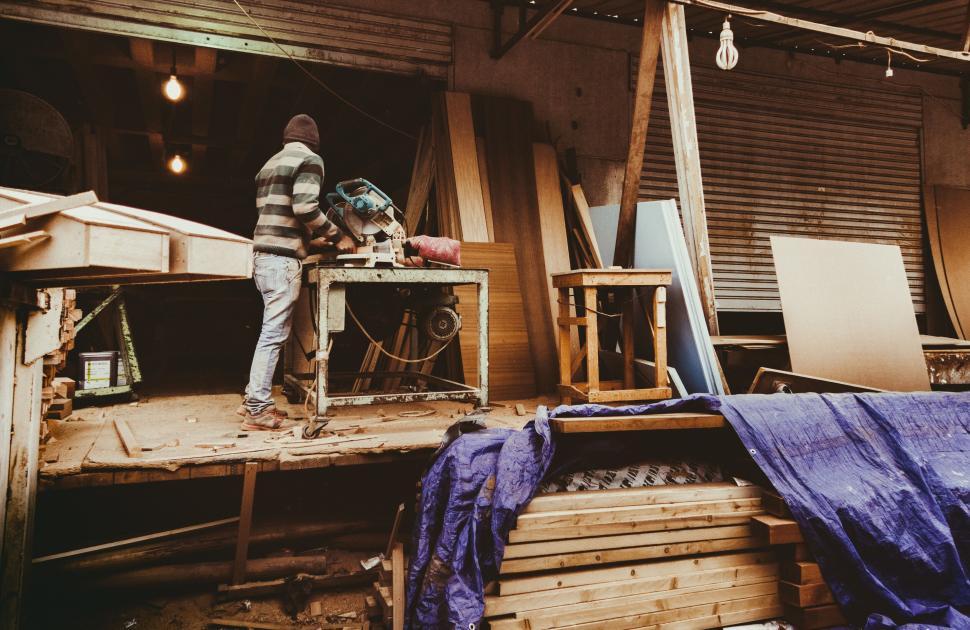 Free Image of Carpenter working in cluttered workshop with machine tools. 