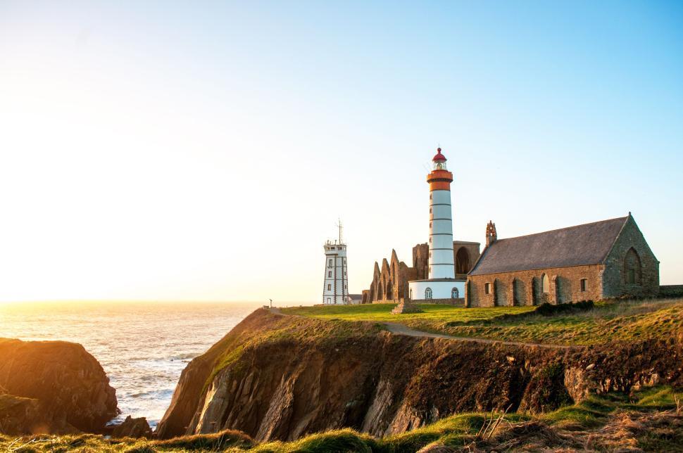 Free Image of Lighthouse with attached buildings against ocean view. 