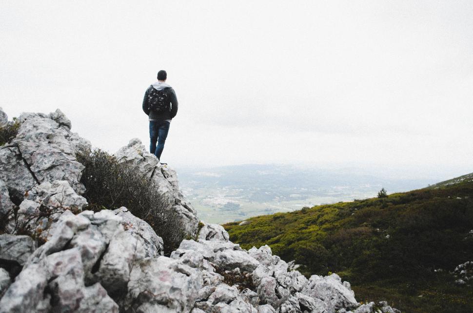 Free Image of Lone hiker standing on rocky mountainous terrain top 