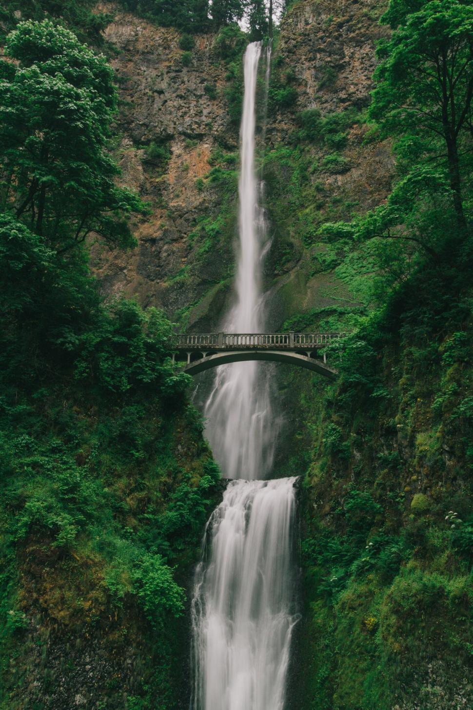 Free Image of Tall waterfall cascading over rocks into a pool below. 