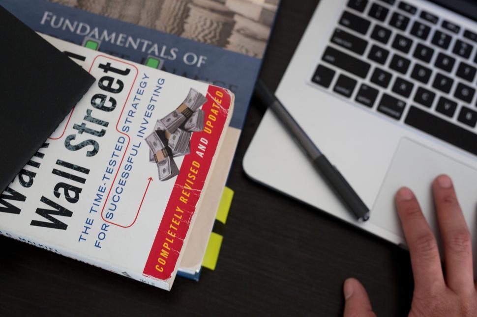Free Image of Books and hand working on laptop on a table 