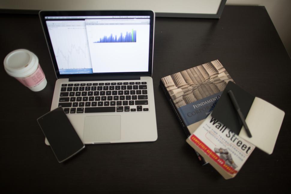 Free Image of Laptop displaying graph with books and coffee on table 
