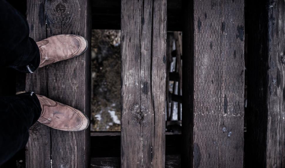 Free Image of Person standing on wooden planks over a gap below 