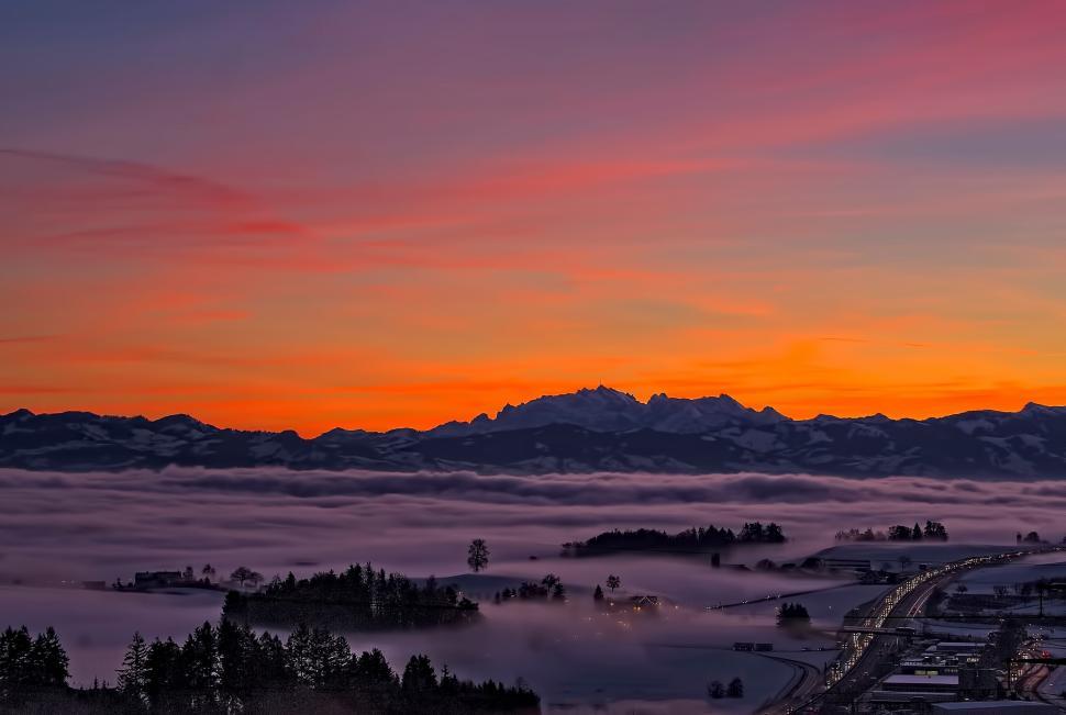 Free Image of Sunset over misty valley with distant mountain range view. 