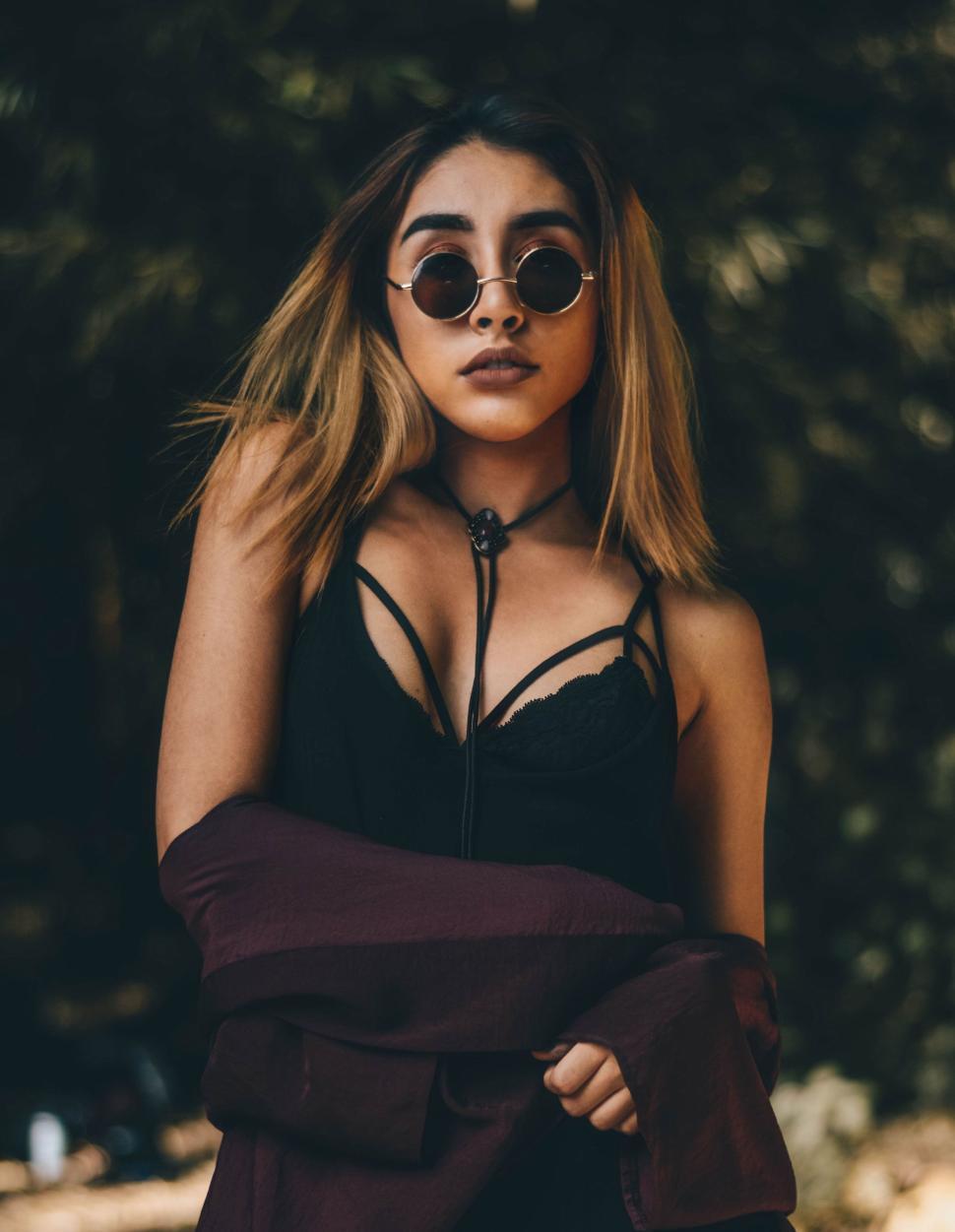 Free Image of Stylish woman with sunglasses in moody forest setting 
