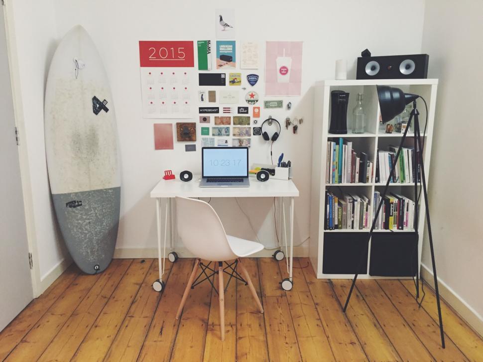 Free Image of Well-organized home office with desk, shelves, surfboard 