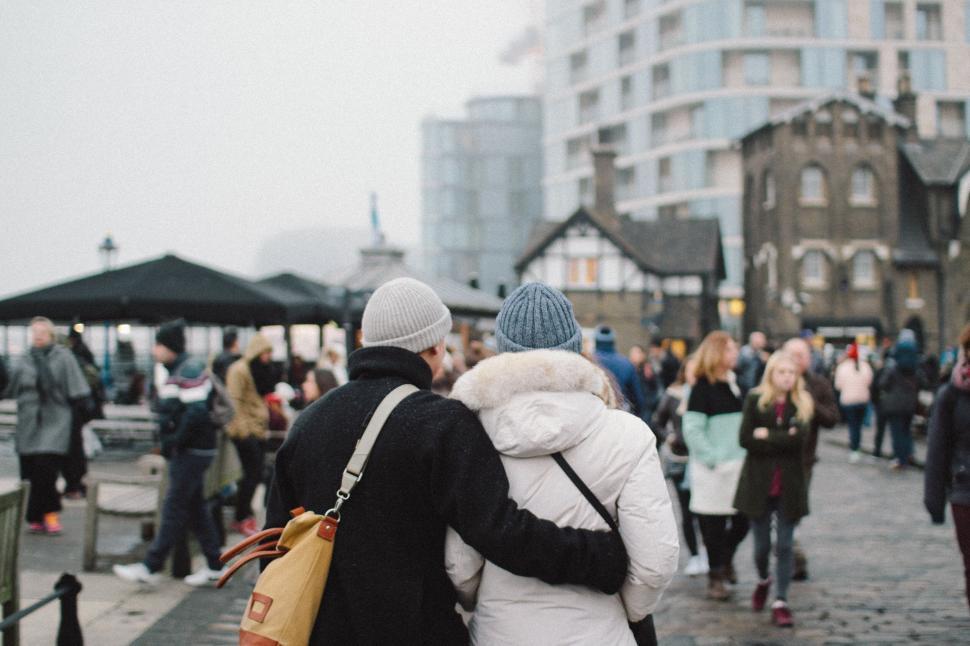 Free Image of Couple embracing among city crowd wearing winter clothes. 