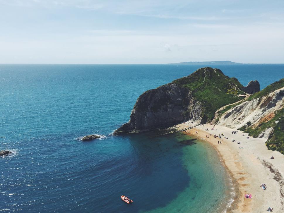 Free Image of Serene beach with clear blue water and rocky coastline. 