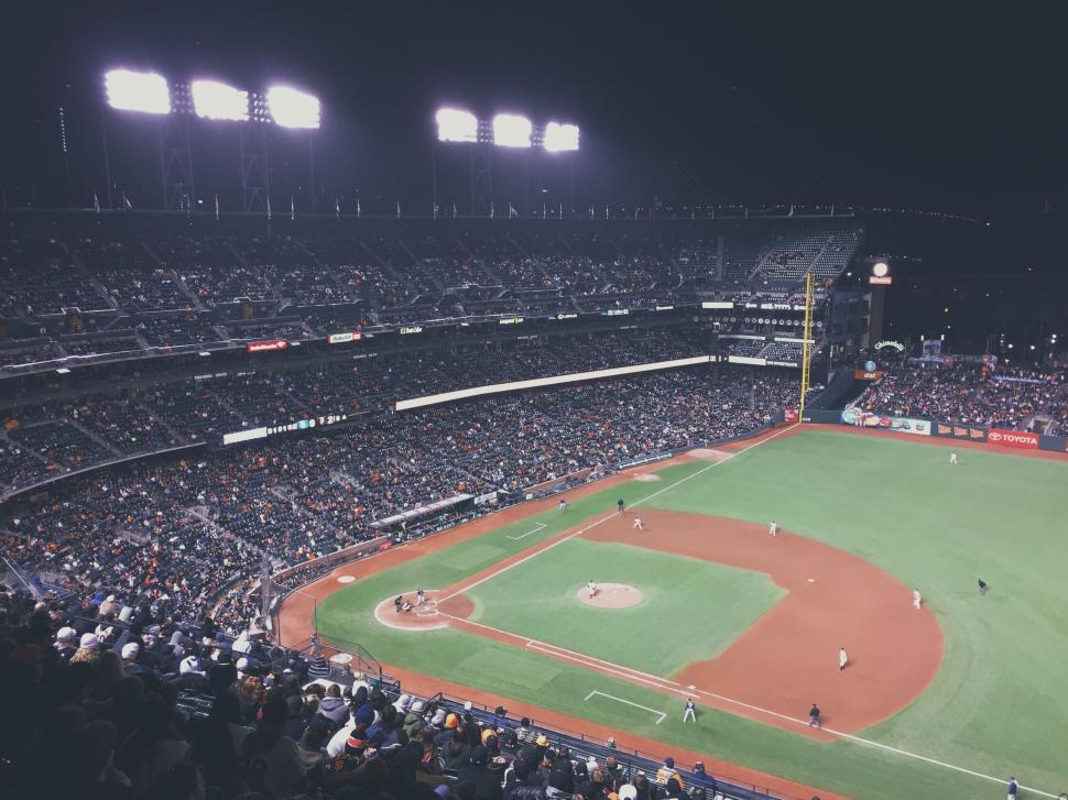 Free Image of Night baseball game in a packed stadium with bright lights 