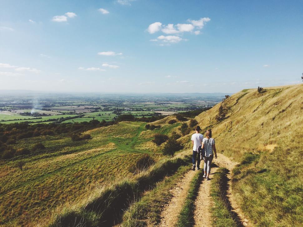 Free Image of Two people walking on a trail in open countryside 