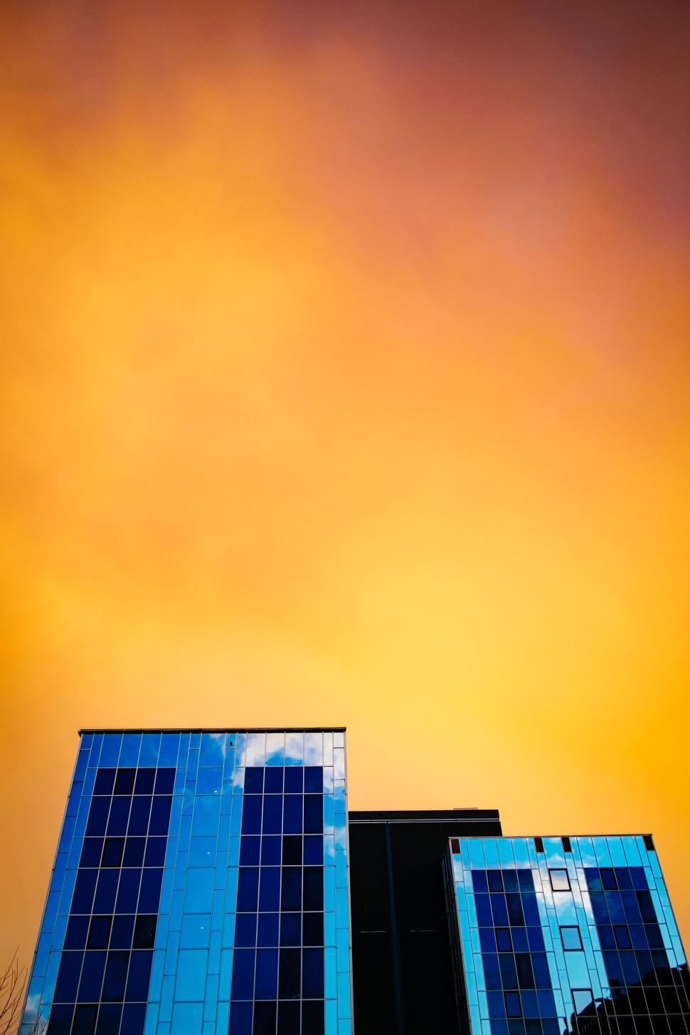 Free Image of Modern blue glass buildings under a colorful sunset sky 