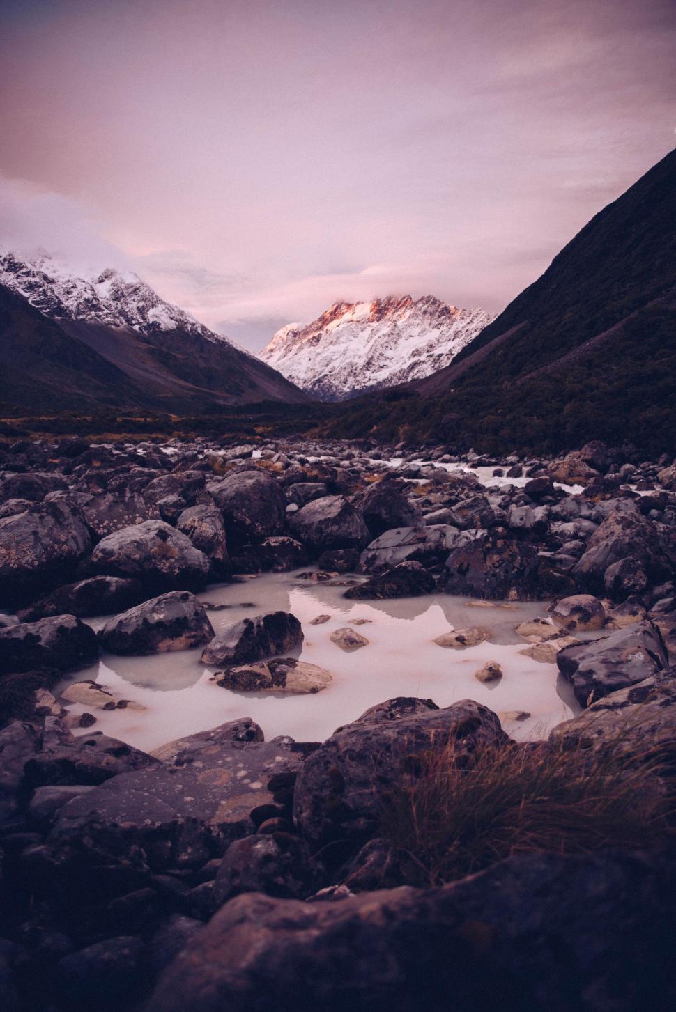 Free Image of Rocky riverbed with mountains in the background at dusk 