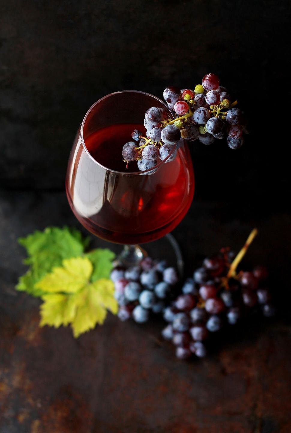 Free Stock Photo of Glass of red wine with grape bunches on a dark surface  | Download Free Images and Free Illustrations