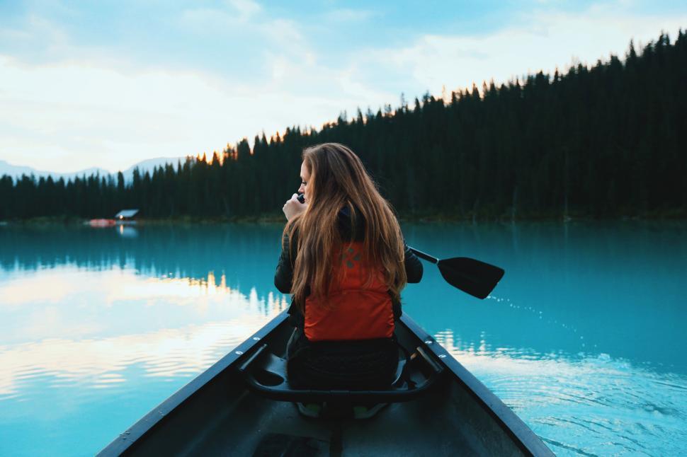 Free Image of Canoe on tranquil lake with forested mountains at dusk 
