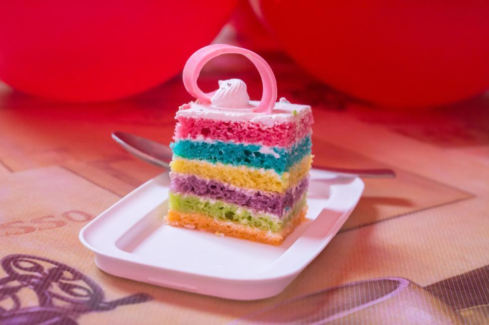 Free Image of Single slice of vibrant rainbow cake with pink swirl 