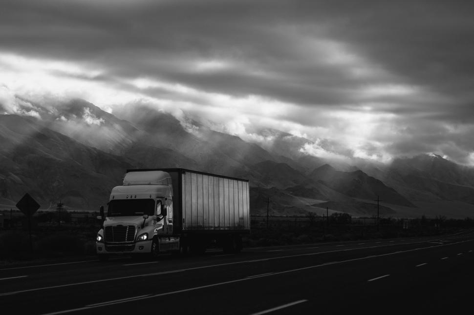 Free Image of Truck driving on an empty road with dramatic skies 