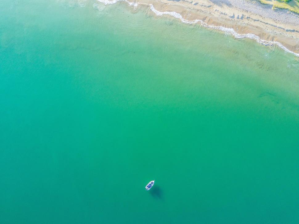 Free Image of Aerial view of small boat on wide green ocean waters. 