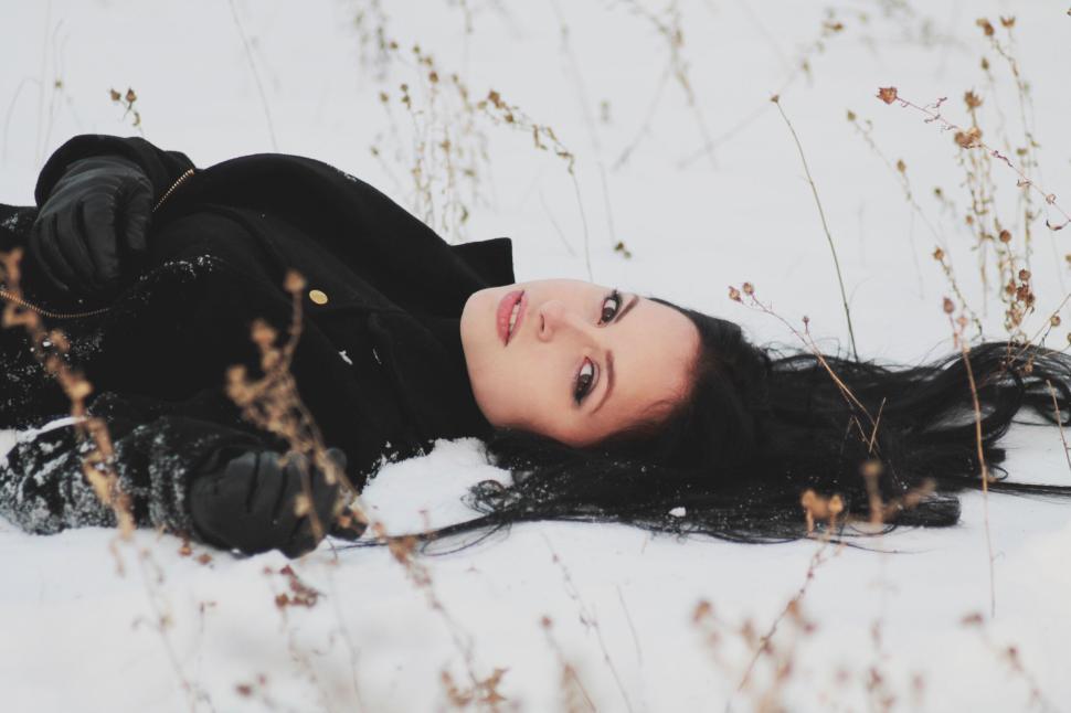 Free Image of Person wearing black coat lying on snowy ground. 