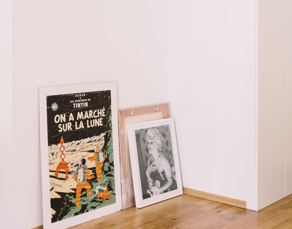 Free Image of Tintin poster and black and white portrait on floor 