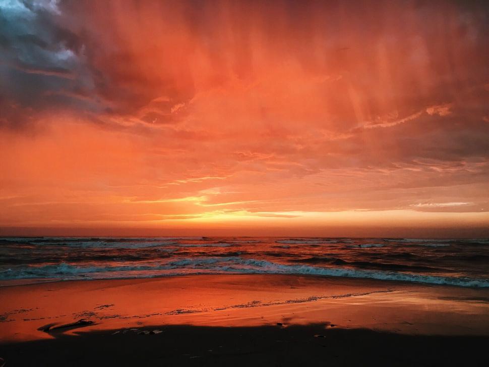 Free Image of Beautiful and dramatic red sunset over the ocean shore. 