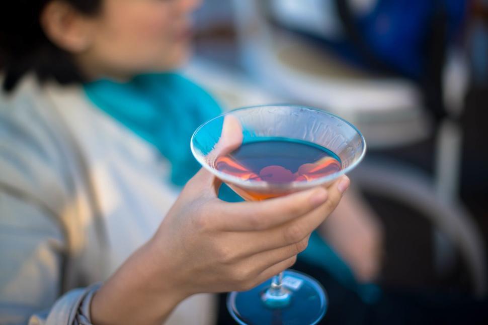 Free Image of Hand holding a martini glass with a drink and a cherry 