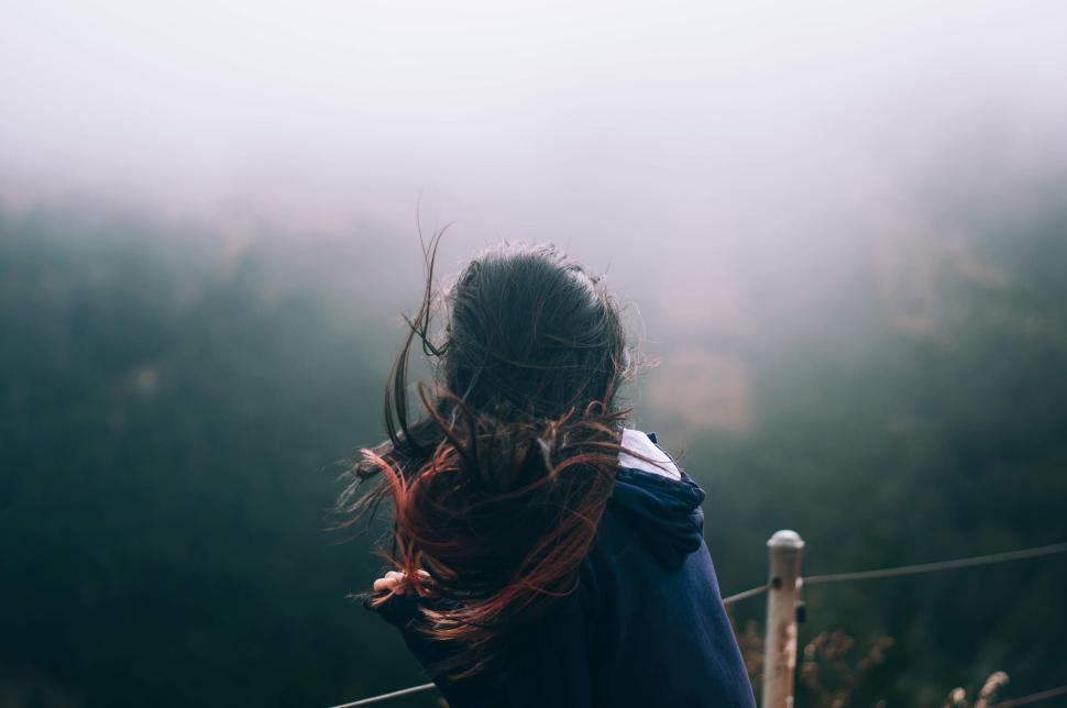Free Image of Woman with windblown hair in misty mountainous landscape 