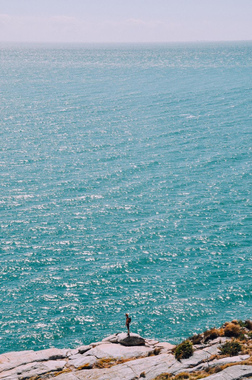 Free Image of Person standing on a rocky cliff overlooking the sea 