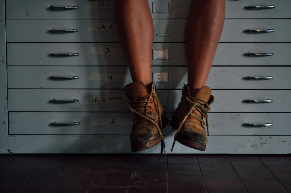 Free Image of Worn-out hiking boots hanging above a metallic cabinet 