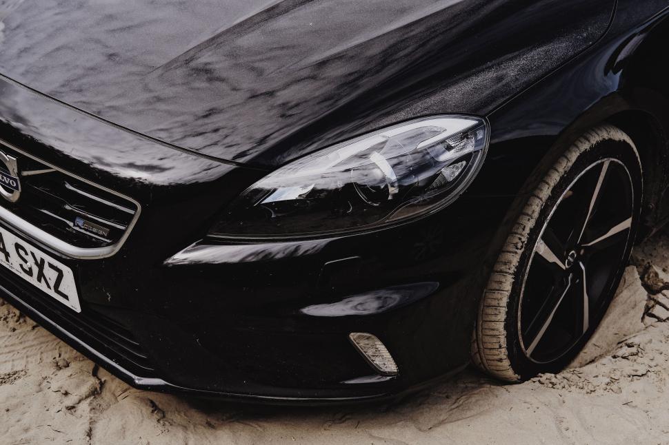 Free Image of Black car parked on sandy beach close-up view 