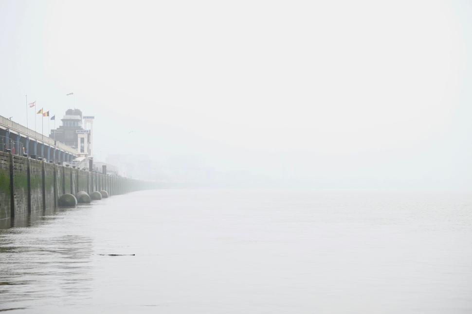 Free Image of Foggy riverbank with distant buildings and minimal view 
