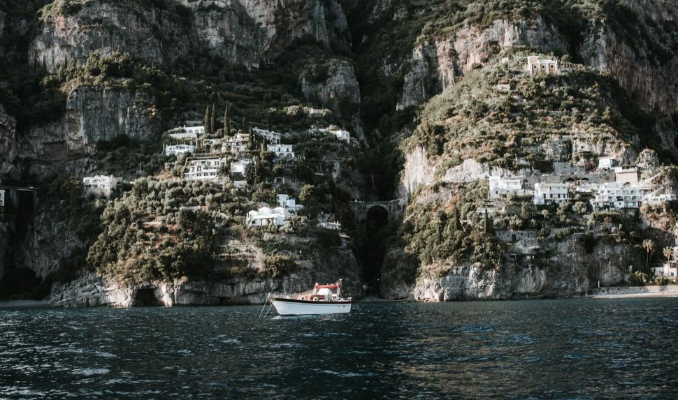 Free Image of Scenic hillside view with a boat on calm blue waters. 