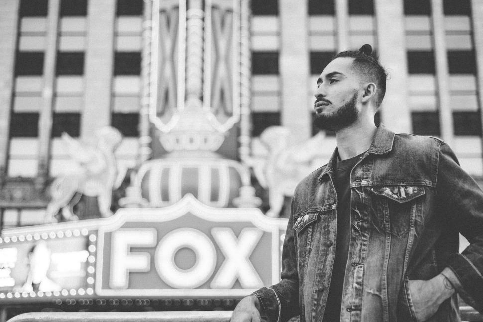 Free Image of Man in denim jacket standing in front of Fox sign 