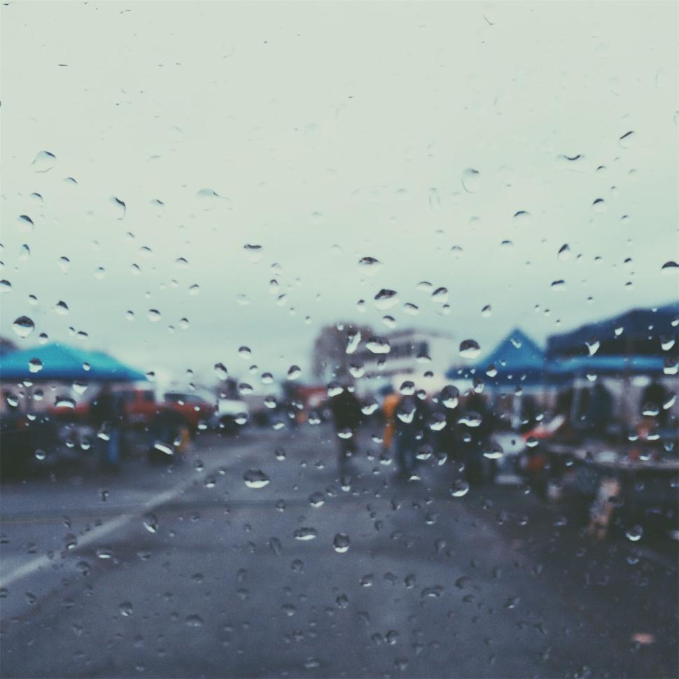 Free Image of Blurred view of a bustling market through rainy window 