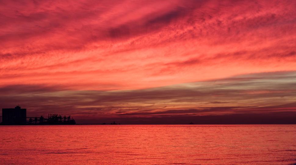 Free Image of Red sunset over calm sea with silhouetted horizon 