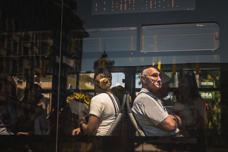 Free Image of Older man and woman with flowers on bus in sunlight 