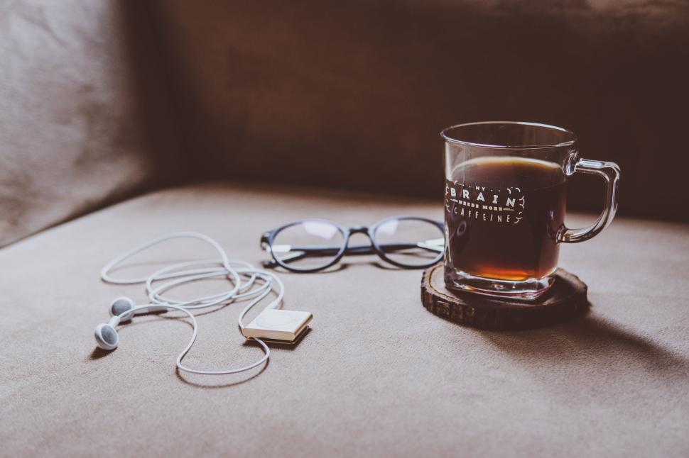 Free Image of Coffee cup, eyeglasses, and earphones on a surface 
