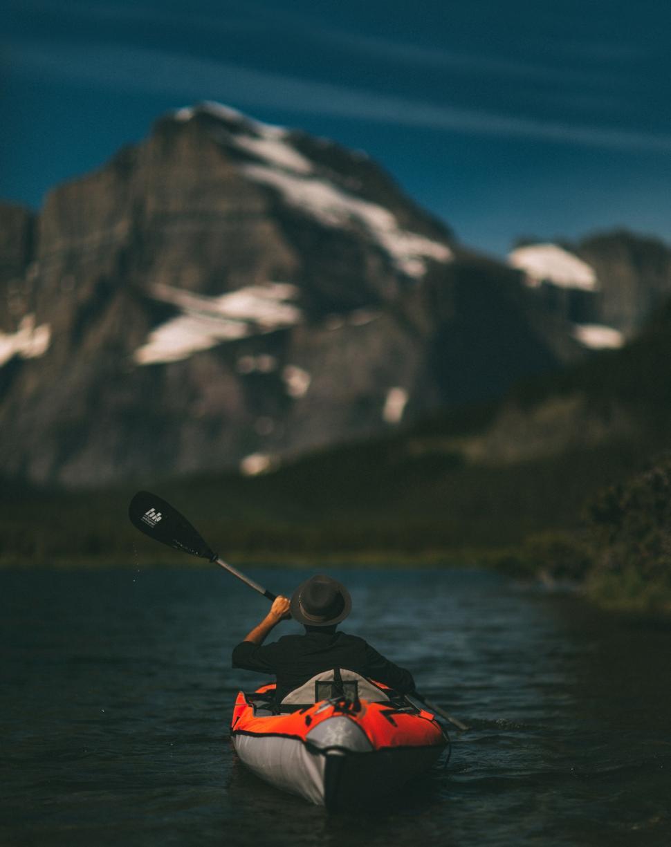 Free Image of Person kayaking in a lake with mountain view background. 
