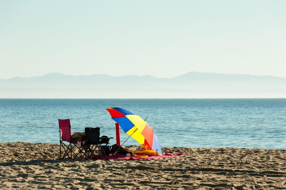 Free Image of Colorful beach umbrella set up on a sandy shore 