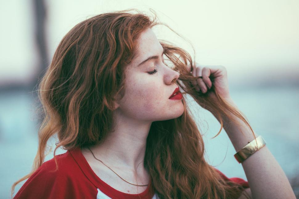 Free Image of Woman with long red hair holding a strand outdoors 