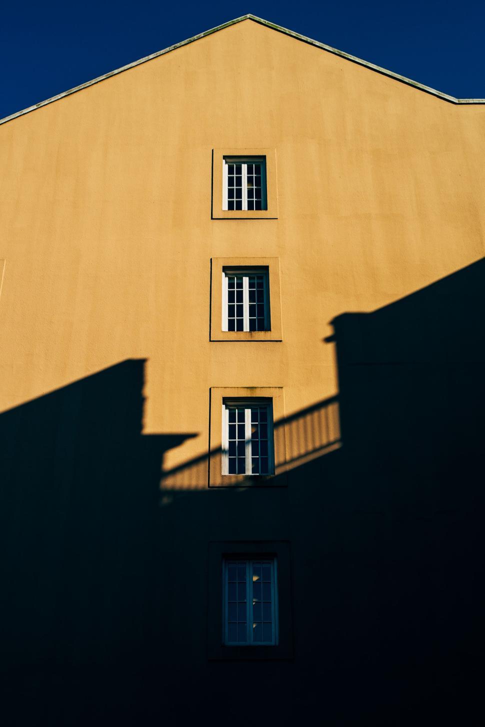 Free Image of Building facade with shadows and symmetrical windows. 